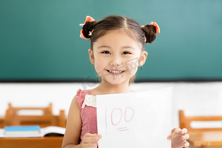 加号加号摄影照片_快乐的小女孩在教室里显示一个加号的试卷