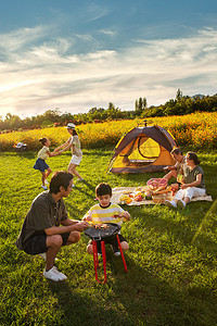 两个孩子的家庭摄影照片_欢乐的一家人在郊外野餐烧烤