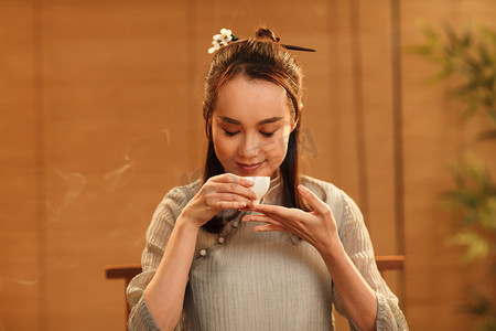 中式衣领摄影照片_青年女人喝茶