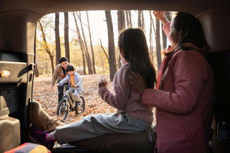 幸福母女在车中向学自行车的父子打招呼