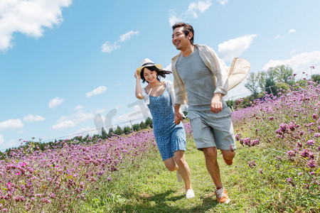 青年夫妇手牵手在花海里奔跑