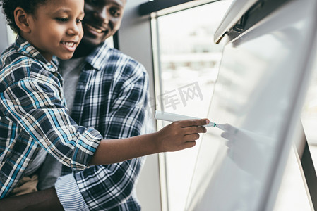 african-american father and son with whiteboard