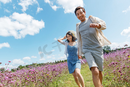 青年夫妇手牵手在花海里奔跑