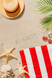 summer水纹摄影照片_top view of striped towel with straw hat and sunglasses on sandy beach