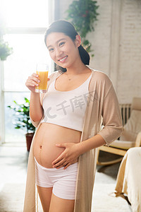 创意橙汁海报摄影照片_孕妇正在喝果汁