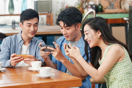 亚洲杯摄影照片_年轻朋友在咖啡馆里玩手机