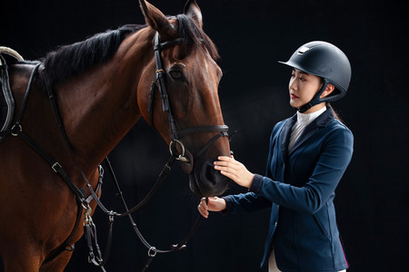 女子骑马摄影照片_触摸马匹的年轻女子