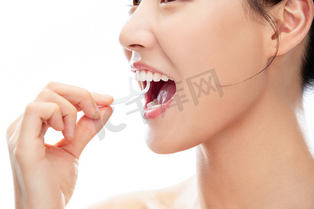 张牙舞爪狮子摄影照片_拿着牙线棒剔牙的青年女人
