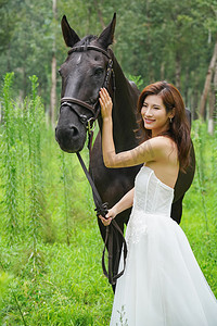 动物马人物摄影照片_树林里漂亮的青年女人牵着马