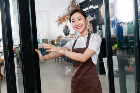 迎接2024牌子摄影照片_咖啡店门口迎接顾客的女服务员