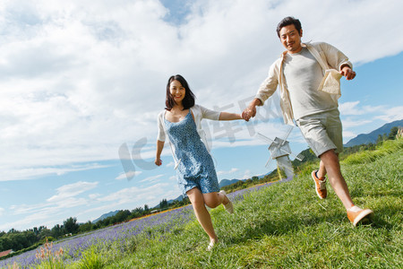 浪漫夫妇手牵手在草地上奔跑