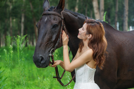 婚纱年轻美女摄影照片_漂亮的年轻女人亲昵的抚摸着马