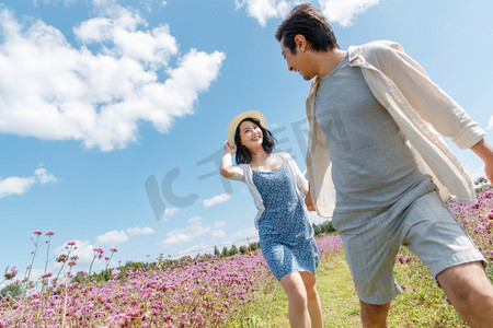 青年夫妇手牵手在花海里奔跑