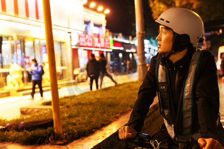 人骑电动车摄影照片_夜晚路边等待订单的代驾员