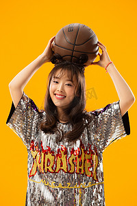 人物背景简洁摄影照片_年轻女孩拿着篮球