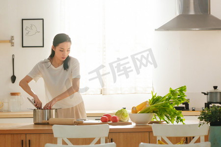 劳动节目录摄影照片_青年女人在厨房里做饭