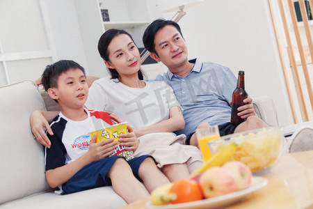 亚洲男孩摄影照片_快乐的一家三口在家看电视