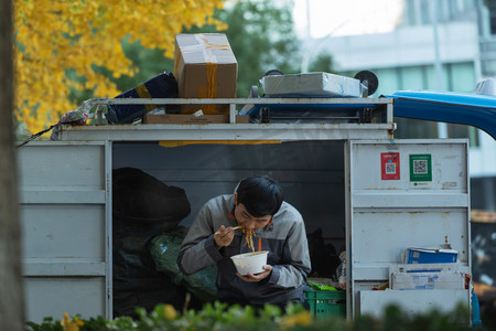 三轮车声摄影照片_快递员坐在快递车上吃面