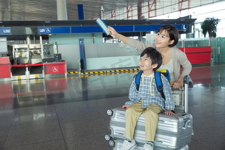 孩子旅游摄影照片_年轻妈妈带着孩子在机场候机大厅