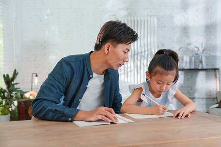 辅导女儿做作业的年轻爸爸