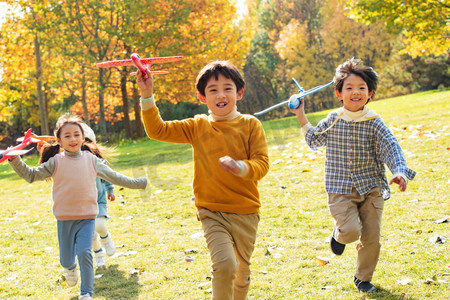 快乐儿童拿着玩具飞机在公园玩耍