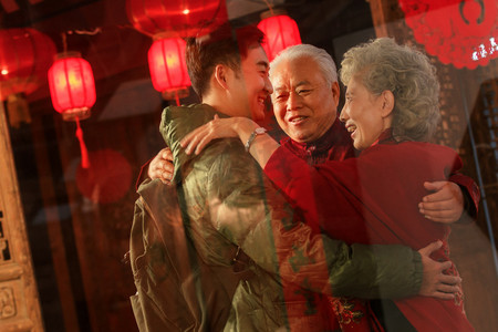 回家红色摄影照片_快乐的青年男人拥抱父母