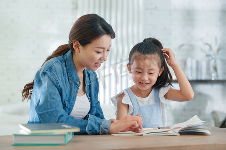 孩子成长摄影照片_辅导女儿做作业的青年女人