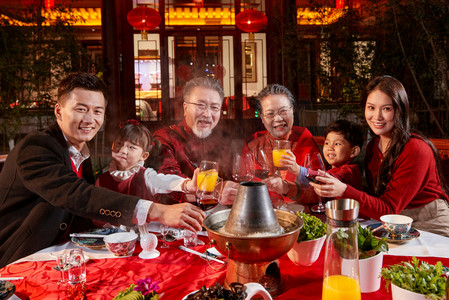 喜庆节日红色元旦摄影照片_东方家庭在中式庭院内干杯庆祝新年