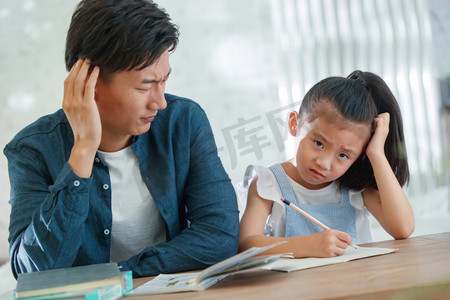 中国家庭的摄影照片_辅导女儿做作业的青年男人