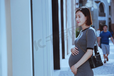 孕妇站在商店橱窗前