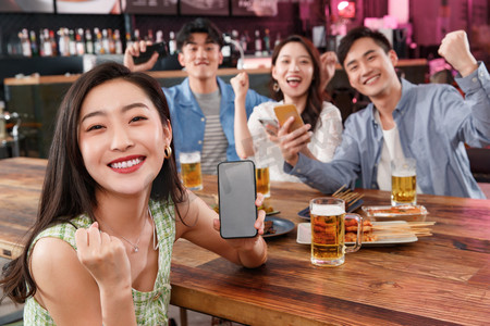 情侣吃饭摄影照片_青年朋友在酒吧喝酒玩手机