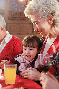 春节传统食物摄影照片_餐桌上祖母喂孙女吃饭