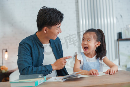 伸手搭车摄影照片_辅导女儿做作业的青年男人