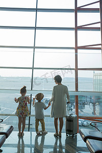 年轻妈妈和孩子在机场候机厅往外看