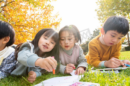 快乐的女孩秋天摄影照片_可爱的小朋友们趴草地上画画