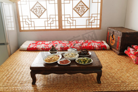 炕桌上的饭菜老年夫妇在家里吃饭看手机去皮的花生米在白瓷碗去皮的