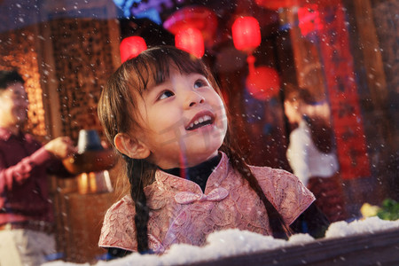 窗外下雪摄影照片_可爱的小女孩看向窗外