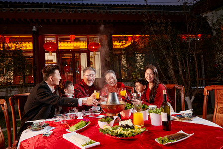 新年吃饭摄影照片_东方家庭在中式庭院内干杯庆祝新年