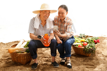 农村直播摄影照片_农民夫妇坐在田头看手机