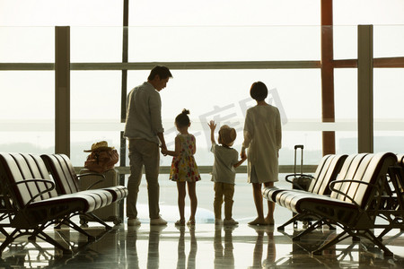 背影窗户摄影照片_幸福家庭在机场候机厅往外看