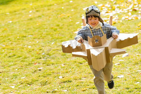 猜灯谜活动摄影照片_快乐的小男孩玩开飞机游戏