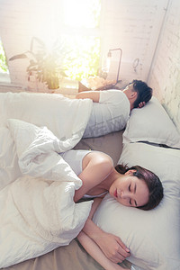 人物背躺摄影照片_年轻情侣在床上睡觉