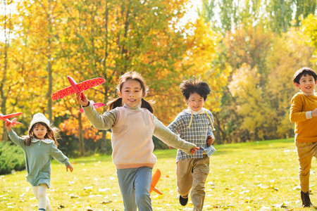飞机度假摄影照片_拿着玩具飞机在公园玩耍的快乐儿童