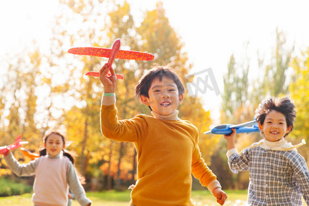 拿着玩具飞机在公园玩耍的快乐儿童