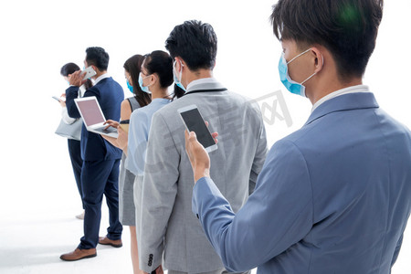 亚洲商务人士摄影照片_排队时看手机的戴口罩的商务人士