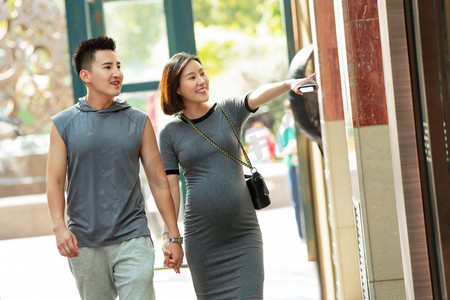 孕妇户外摄影照片_丈夫陪着怀孕的妻子逛街购物
