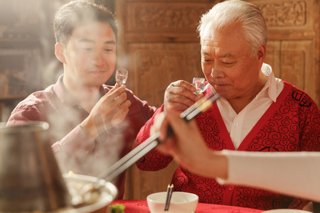 中国风锦鲤红色摄影照片_幸福父子吃年夜饭喝酒