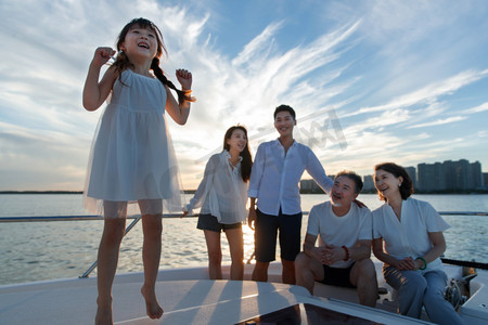 海边夕阳天空摄影照片_夕阳下在游艇上的快乐一家人