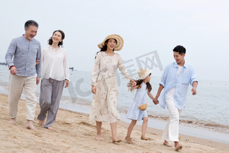 海滩游玩摄影照片_快乐的一家人在海滩上散步