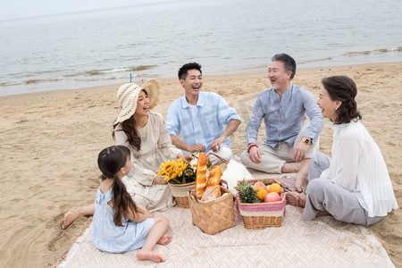 海滩游玩摄影照片_在海边度假的一家人野餐